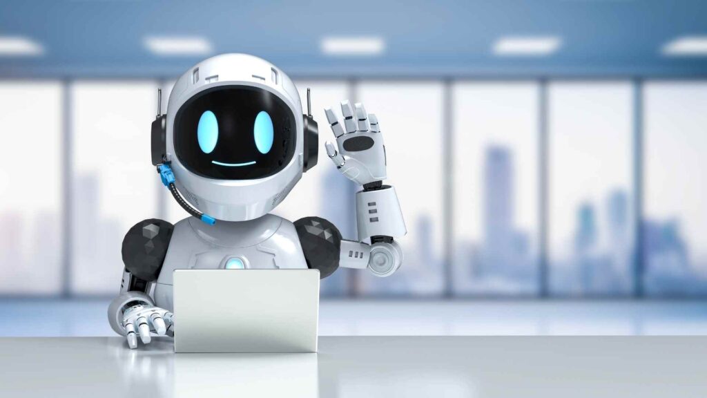 A friendly humanoid robot sitting at a desk with a laptop, waving and smiling in a modern office environment, representing artificial intelligence, technology, and digital assistance.