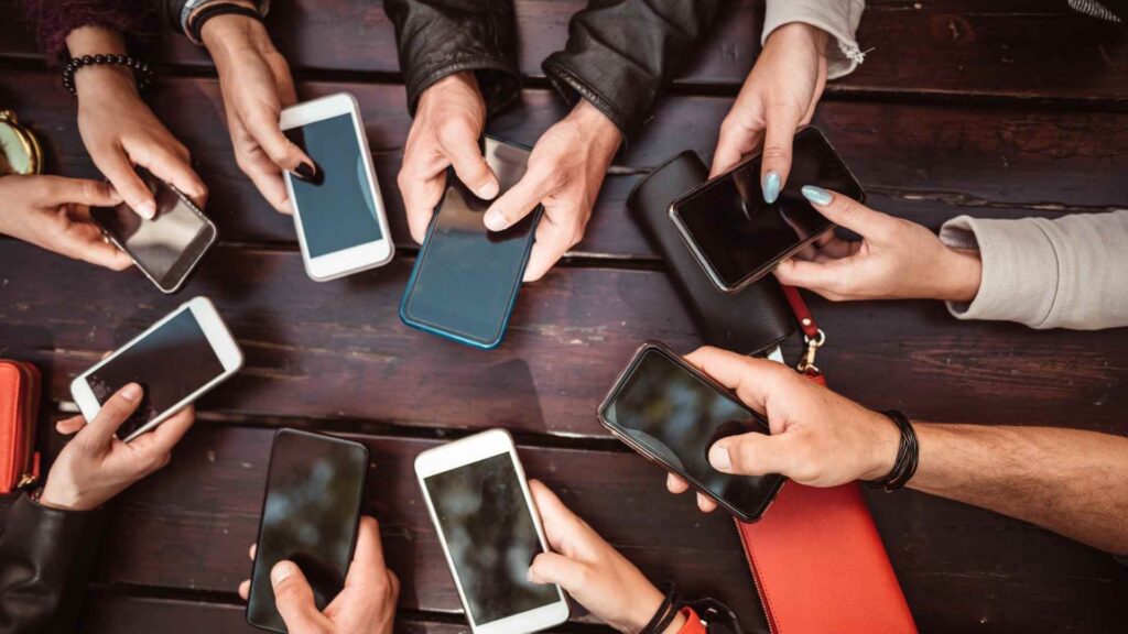 Several people sitting around a table holding smartphones, viewed from above