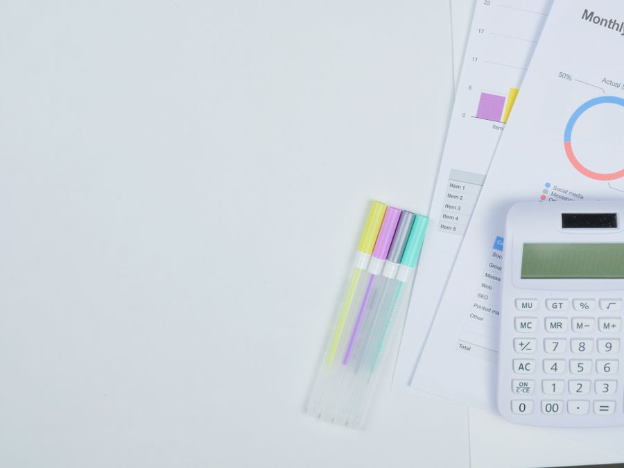 Minimalist office desk with a calculator, budget planning documents, and colorful pens.