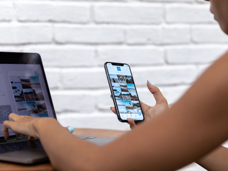 A woman working remotely using a laptop and smartphone, focusing on social media content.
