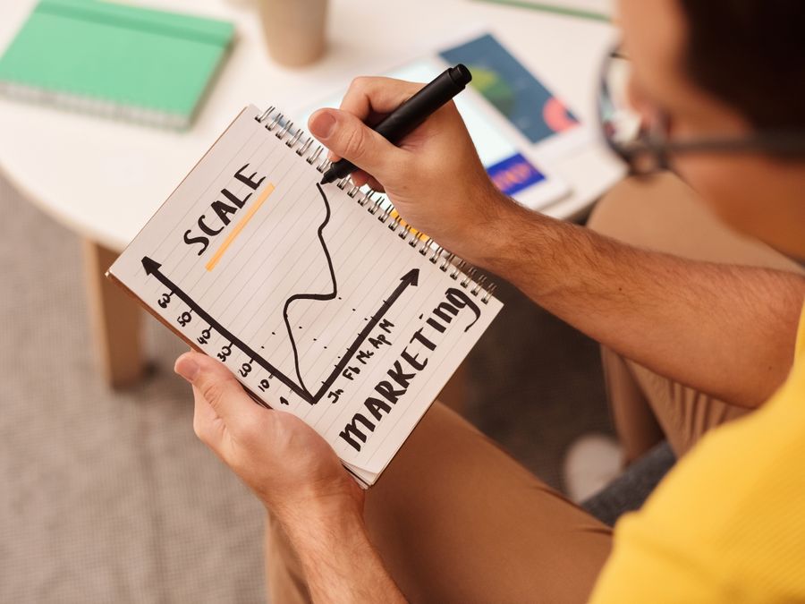 Close-up of a man drawing a marketing strategy graph in a notebook.
