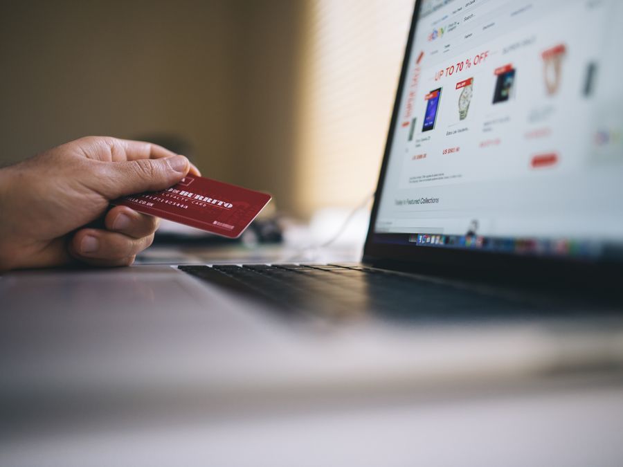 Person holding a credit card while shopping online on a laptop, indicating ecommerce transactions.