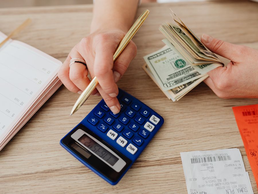 Hands handling cash and calculator for budget planning. Modern financial scene.