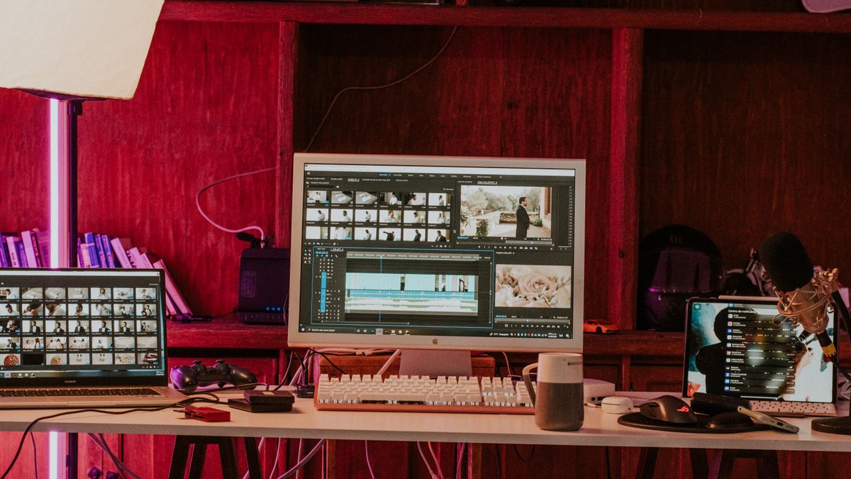 A professional video editing workspace featuring monitors, keyboard, and microphones in a studio setting.