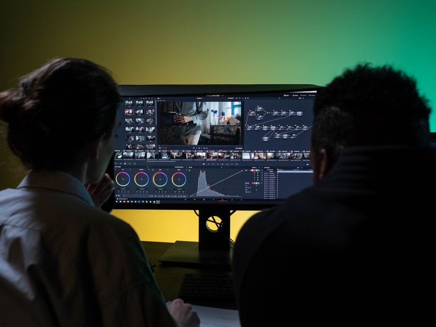 Team of two professionals video editing in a modern setup with dual monitors.