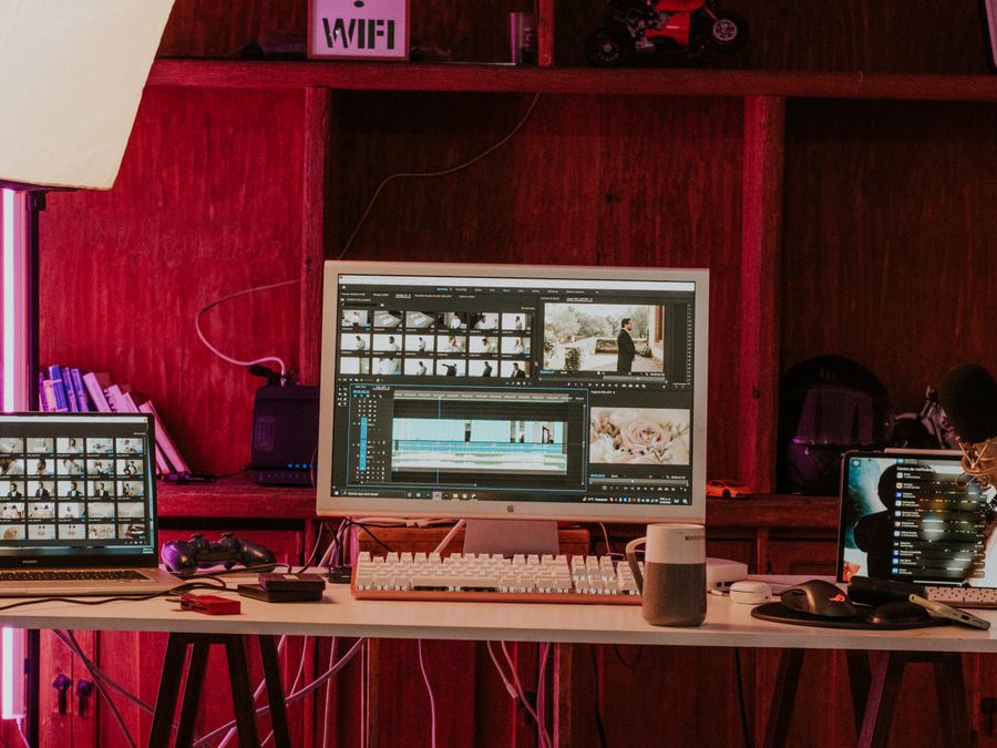 A professional video editing workspace featuring monitors, keyboard, and microphones in a studio setting.