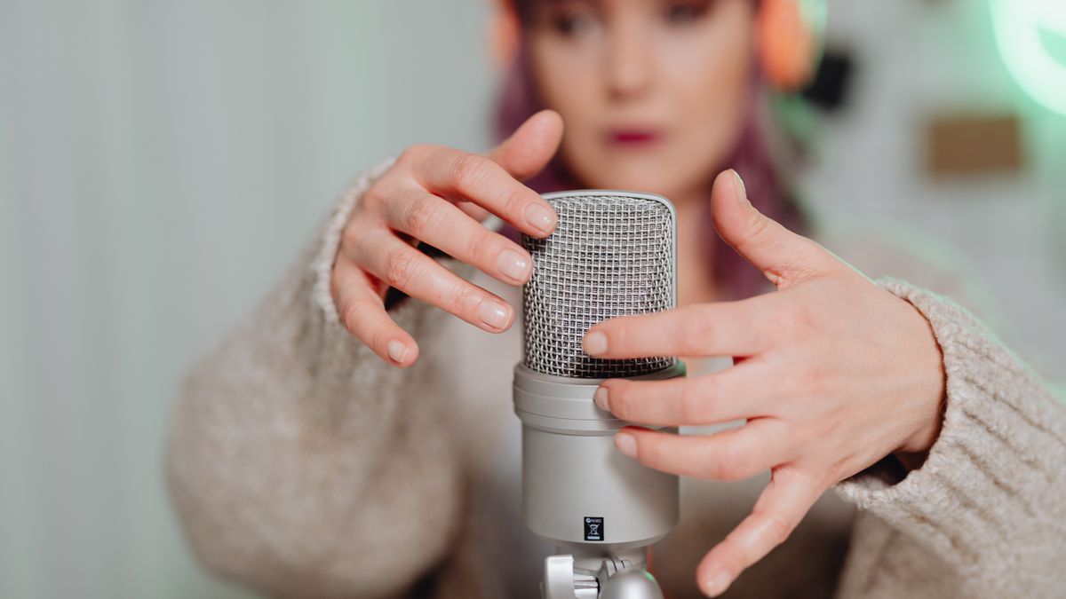 Woman recording ASMR using a microphone in a calm indoor setting.