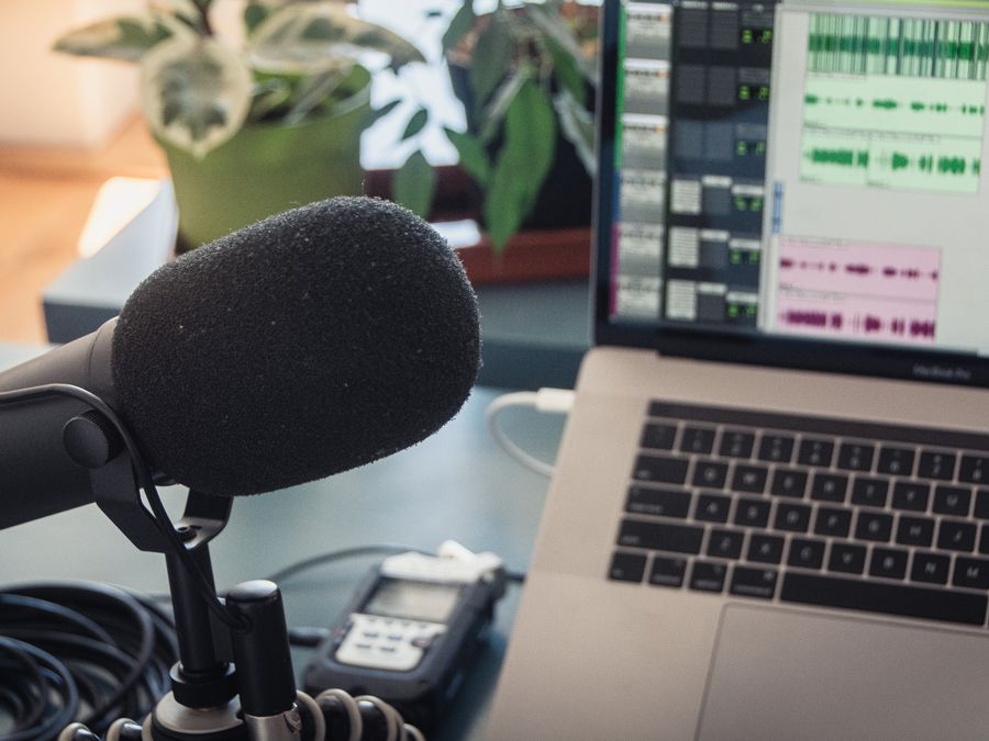 A podcast recording setup with a laptop, microphone, and audio equipment indoors.