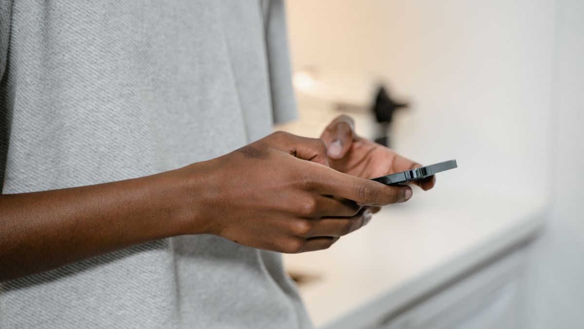 A person texting on a smartphone indoors, showing hands and device close-up.