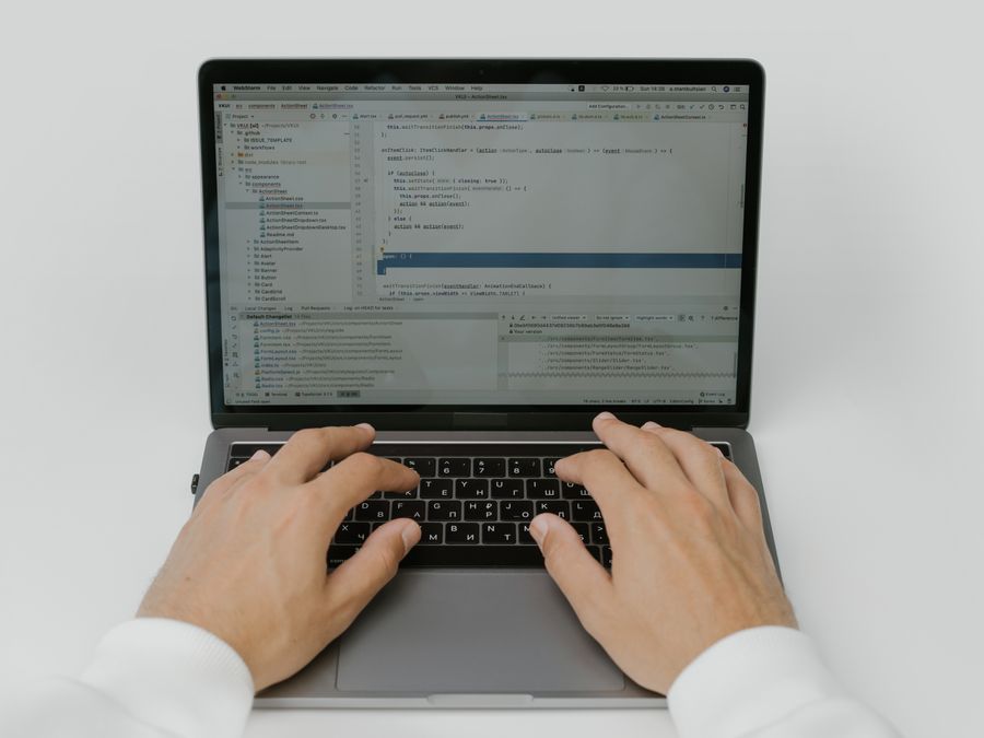 Close-up of hands coding on a laptop, showcasing software development in action.