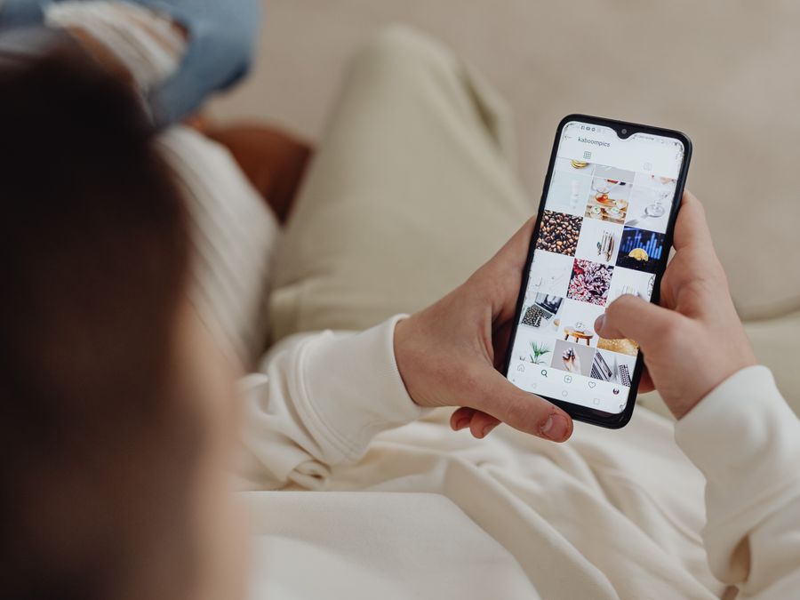 Person using smartphone to browse Instagram indoors, showing social media engagement.