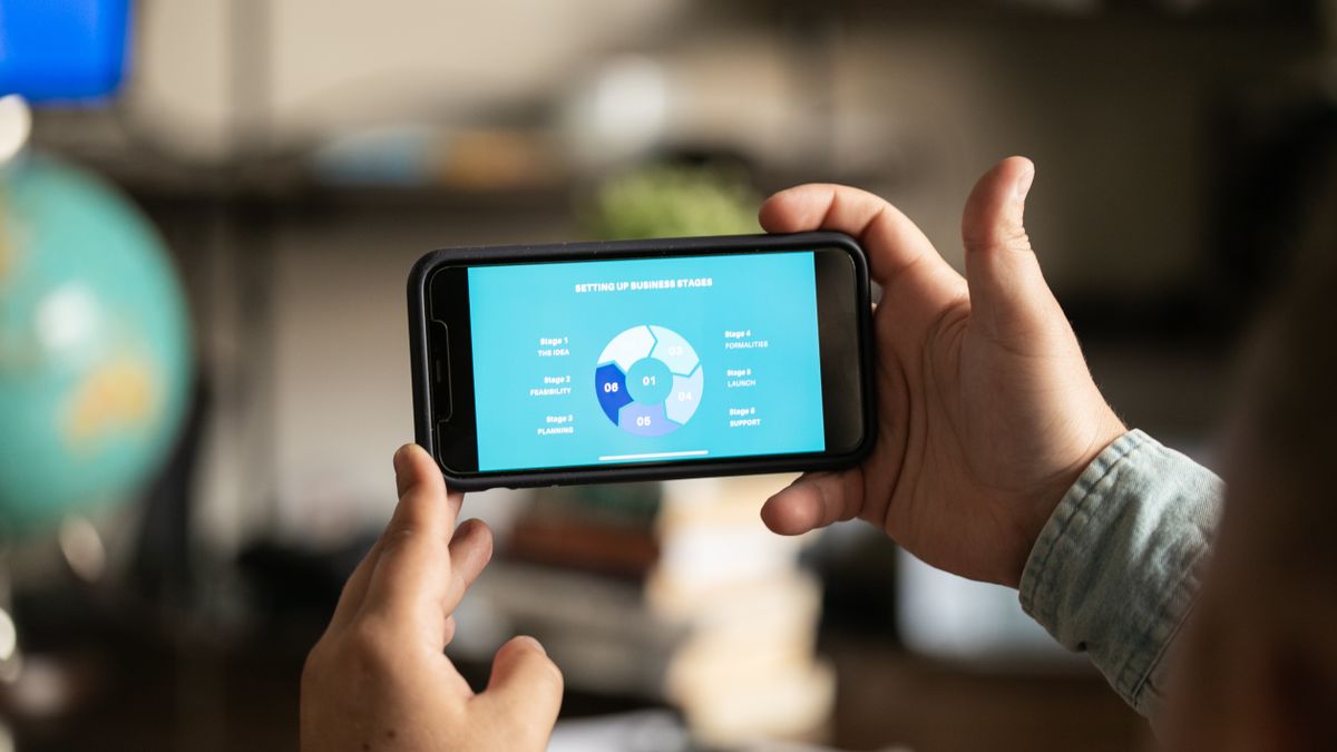 Close-up of hands holding a smartphone displaying a business chart indoors.