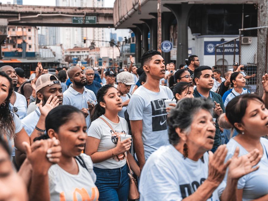A large group of diverse people gathered outdoors, engaging in a community event in an urban setting.