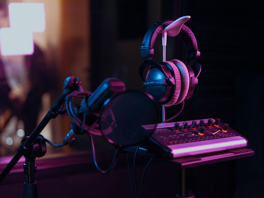 High-quality audio recording studio setup with a microphone, headphones, and mixer board in dim lighting.