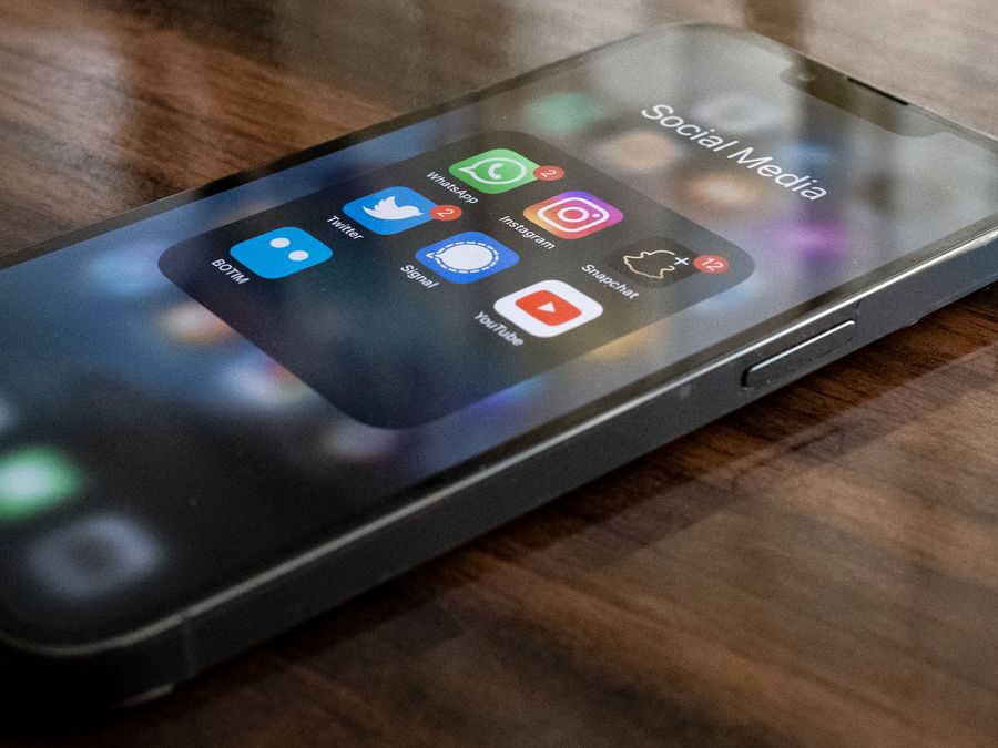 Close-up of smartphone on table showing various social media app icons including WhatsApp and Instagram.