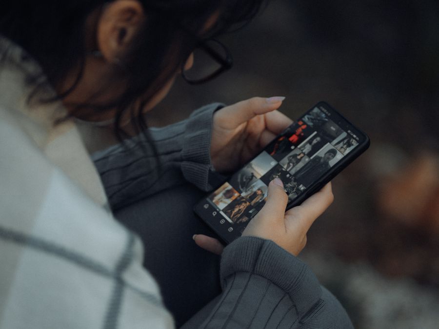 Young woman browsing photo gallery on smartphone outdoors, showcasing technology and lifestyle.