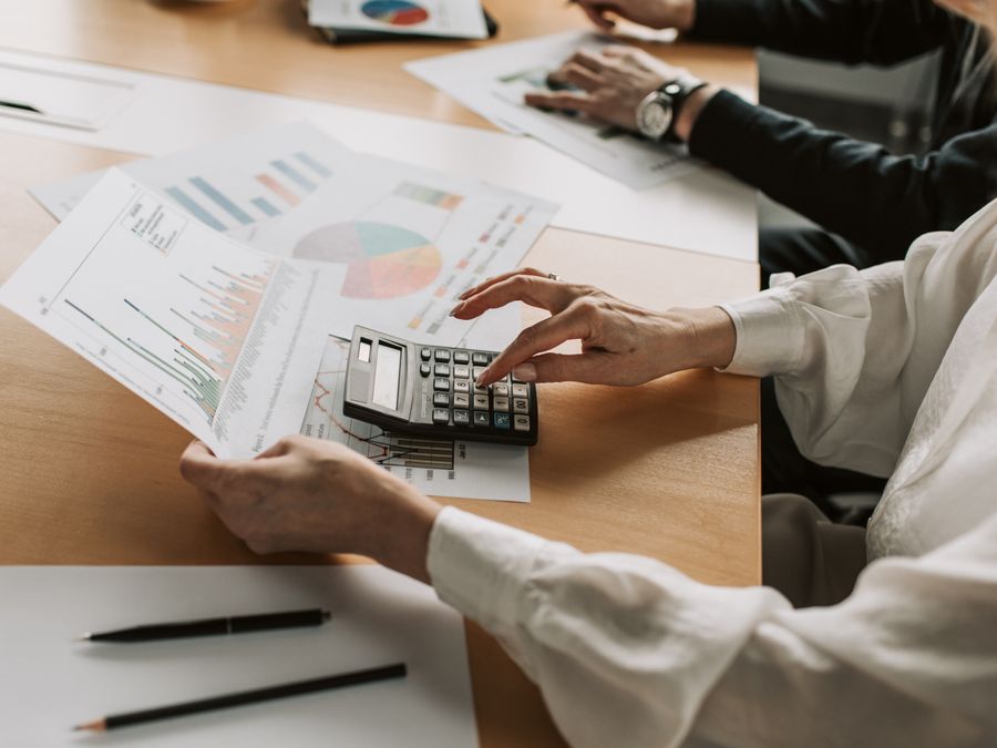 Hands performing financial calculations with charts and a calculator at a meeting table.