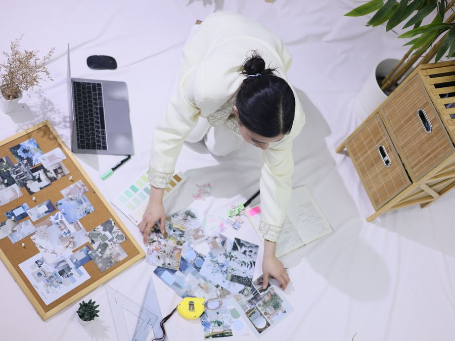 Overhead view of a person working in a creative space with a mood board, planner, and laptop.
