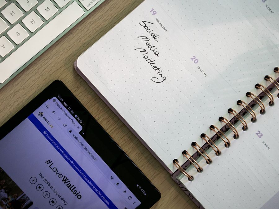 Top view of a notebook, tablet, and keyboard used for social media marketing planning.