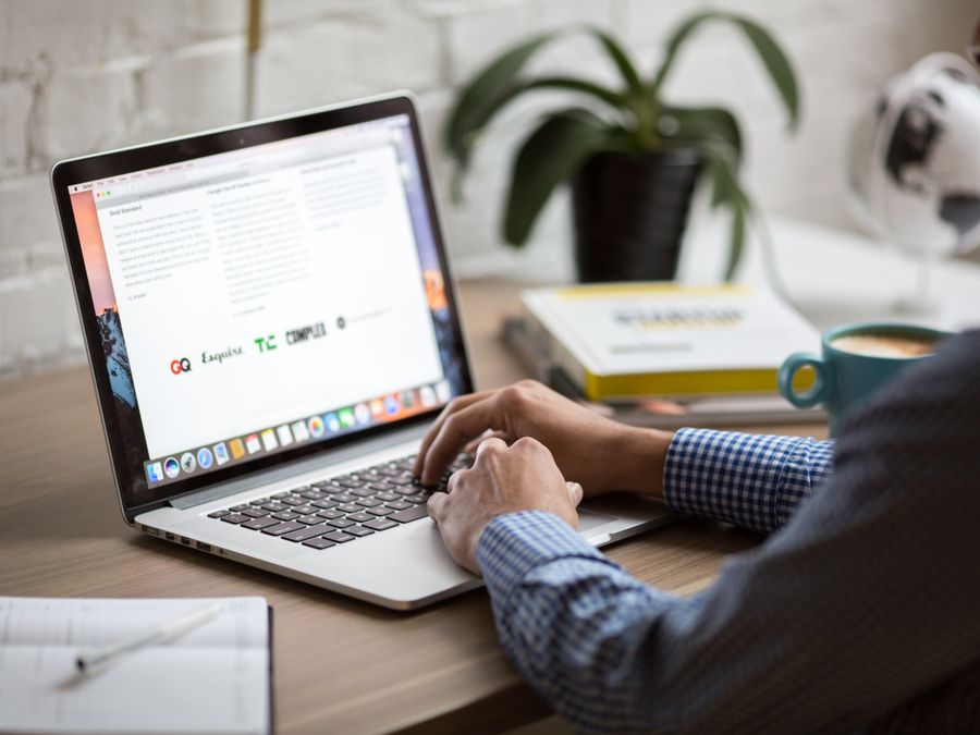A man working on a laptop at a desk with coffee, showcasing remote work in a modern office setting.