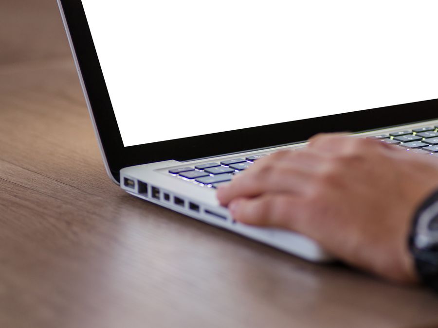 Close-up of a hand using a laptop with a blank screen, ideal for adding custom content.