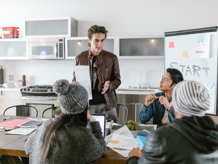 Young professionals discussing ideas around a table in a stylish office space, emphasizing teamwork and innovation.