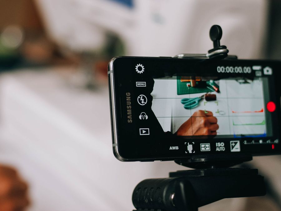 Smartphone on tripod capturing person writing on paper, showing content creation process.