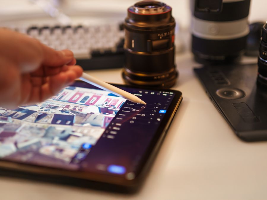 A detailed view of a professional photography editing setup with tablet and lenses.