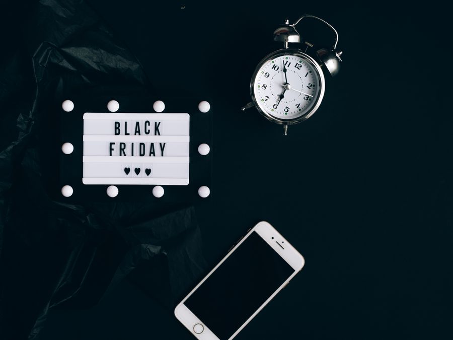 Stylish Black Friday promotion with alarm clock and smartphone on dark background.