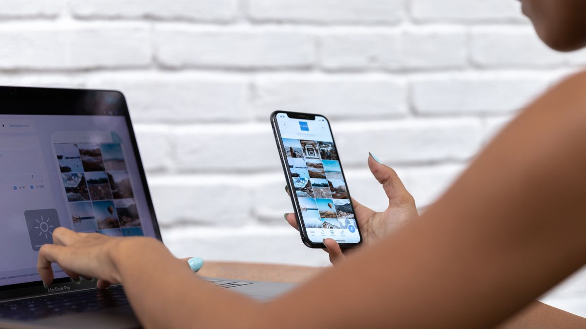 A woman working remotely using a laptop and smartphone, focusing on social media content.