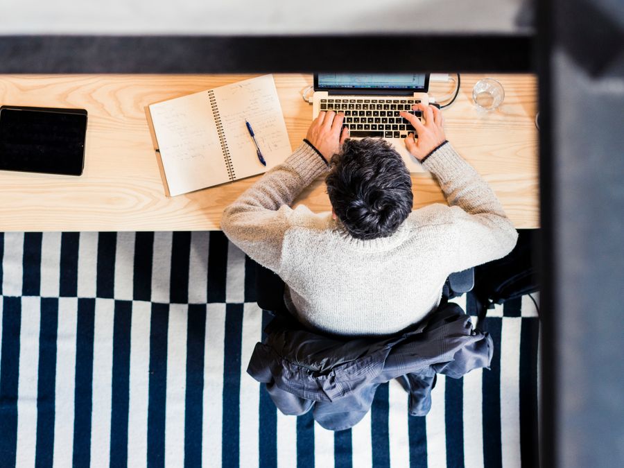 A top view of a person working on a laptop at a desk, emphasizing modern office technology.
