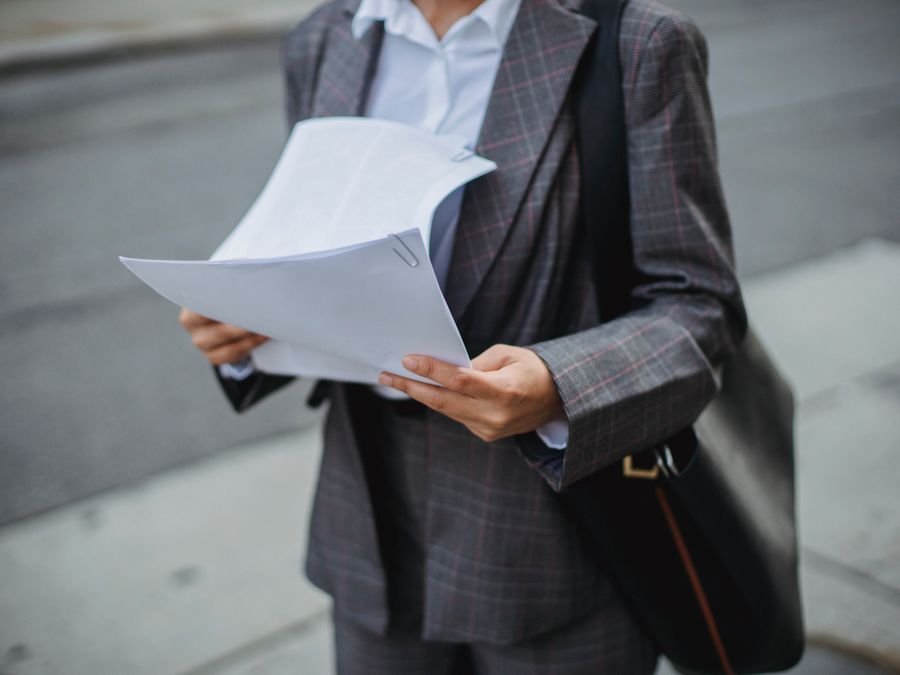Professional businesswoman reviewing documents outdoors in a city environment.