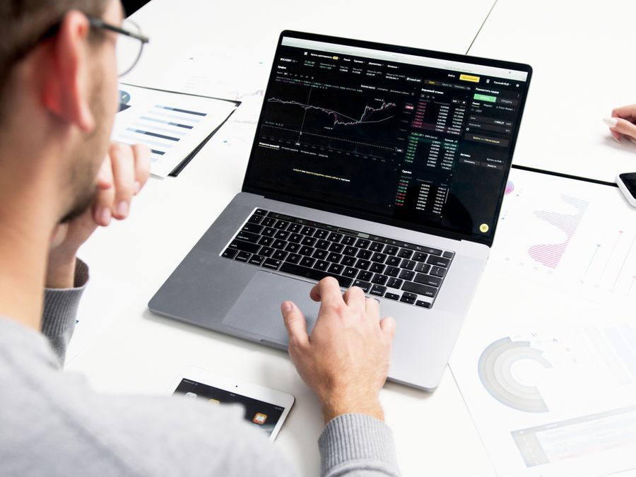 Business professional analyzing stock market data on a laptop for investment insights.