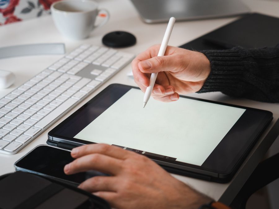Designer working with a tablet and stylus in a modern workspace setup.