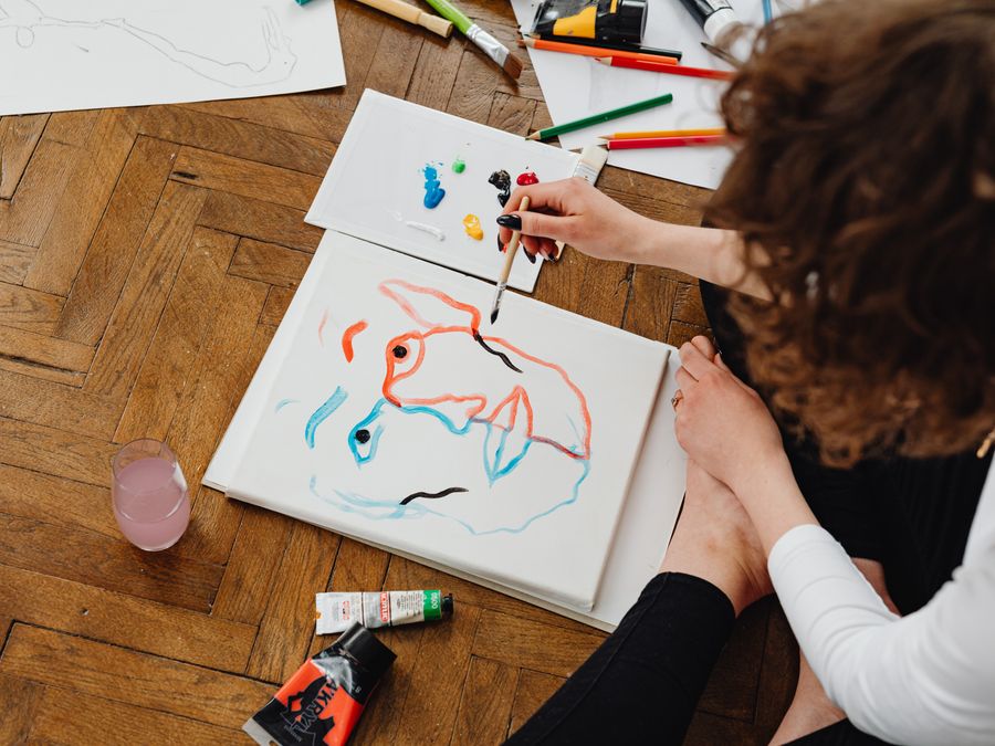 Artist painting abstract face on canvas with vibrant colors.