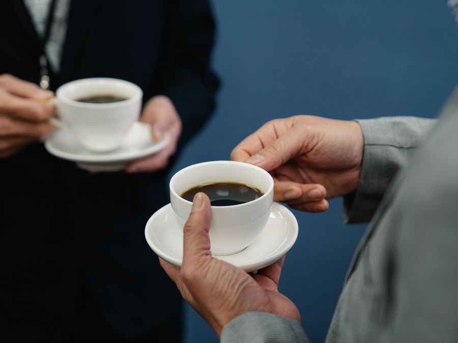 Businessmen in suits holding coffee cups during a casual meeting indoors.