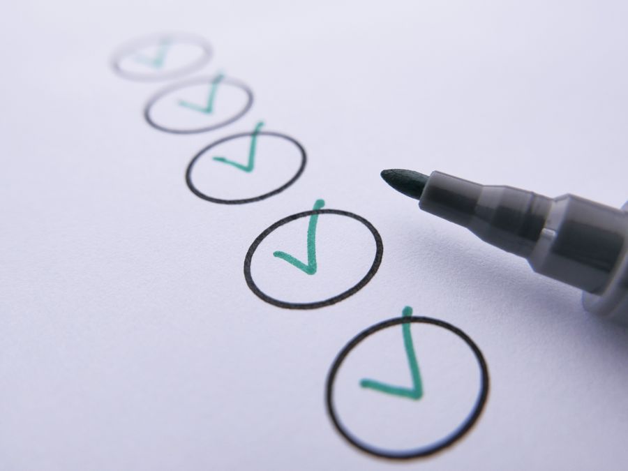 Close-up of a checklist with green checkmarks on white paper using a marker.