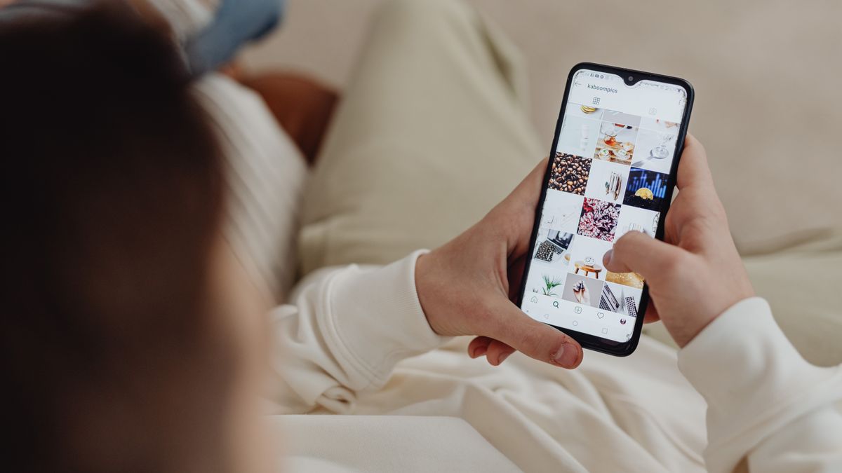 Person using smartphone to browse Instagram indoors, showing social media engagement.