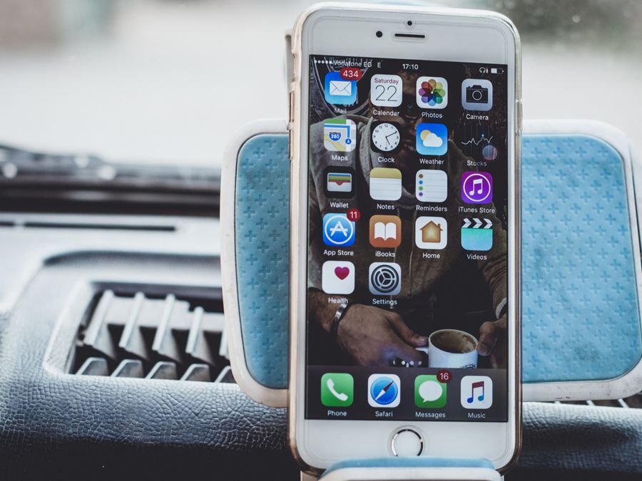 Close-up of a smartphone mounted on a car dashboard showing home screen with apps.