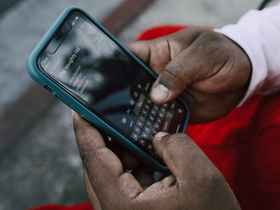 A person typing on a smartphone displaying a list titled 'The naughty list'.