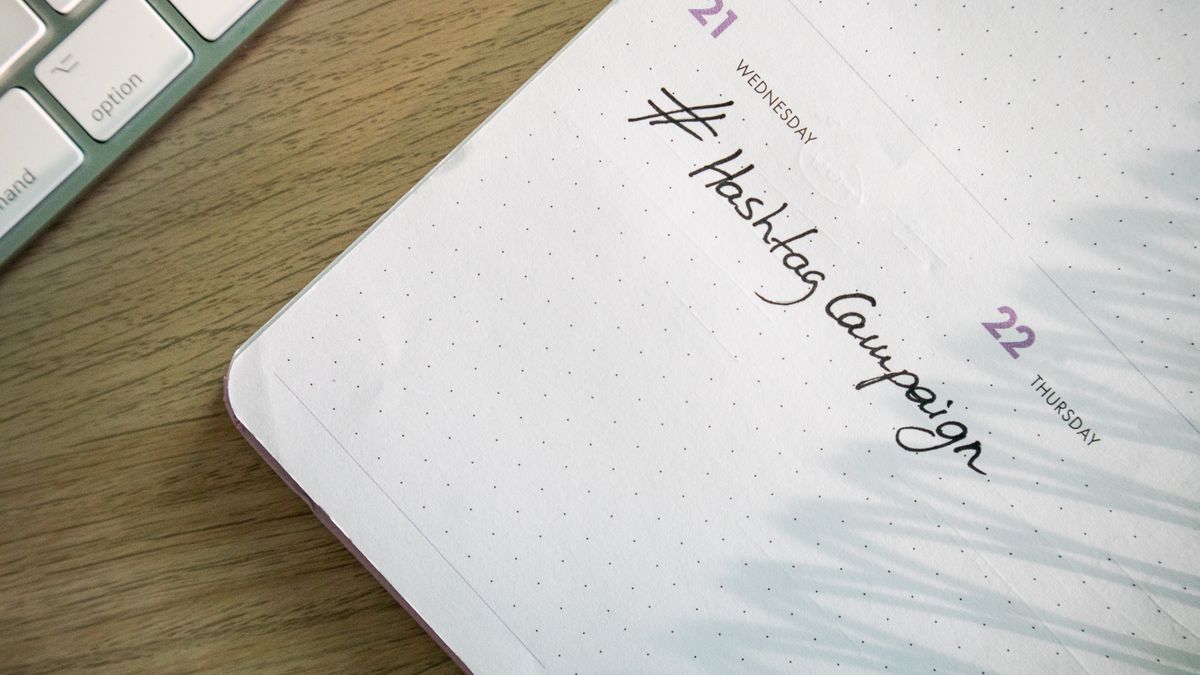 Open planner with 'Hashtag Campaign' handwritten next to keyboard. Ideal for social media and productivity themes.