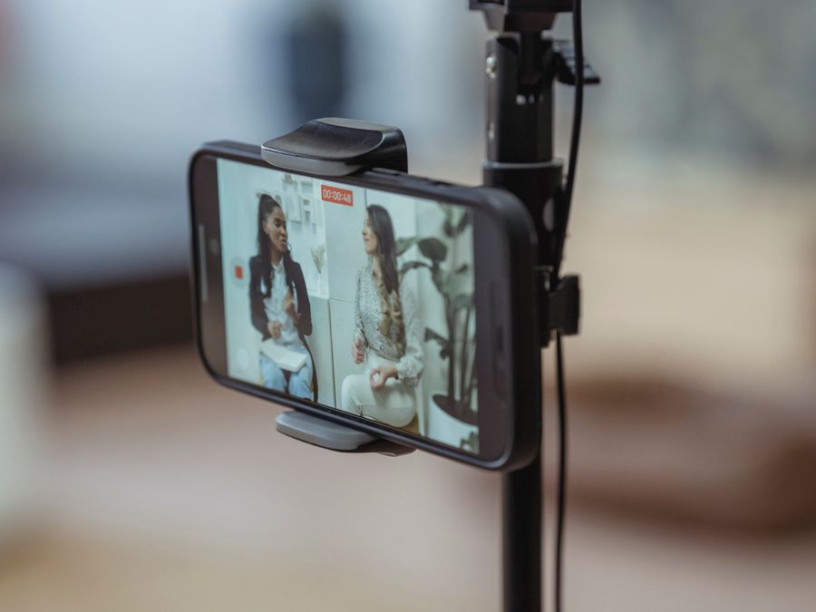 Modern smartphone on tripod recording video of content stylish women having friendly conversation