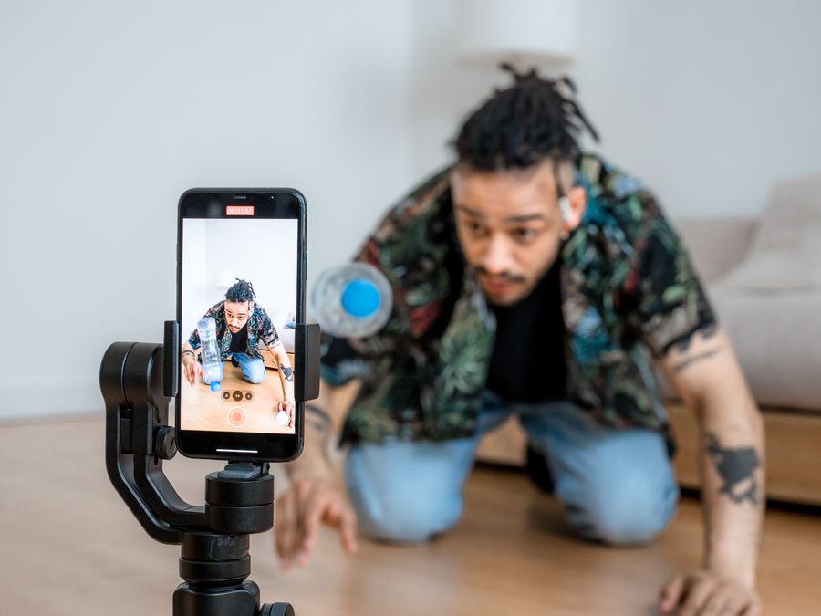 Man filming creative content with smartphone on gimbal indoors.