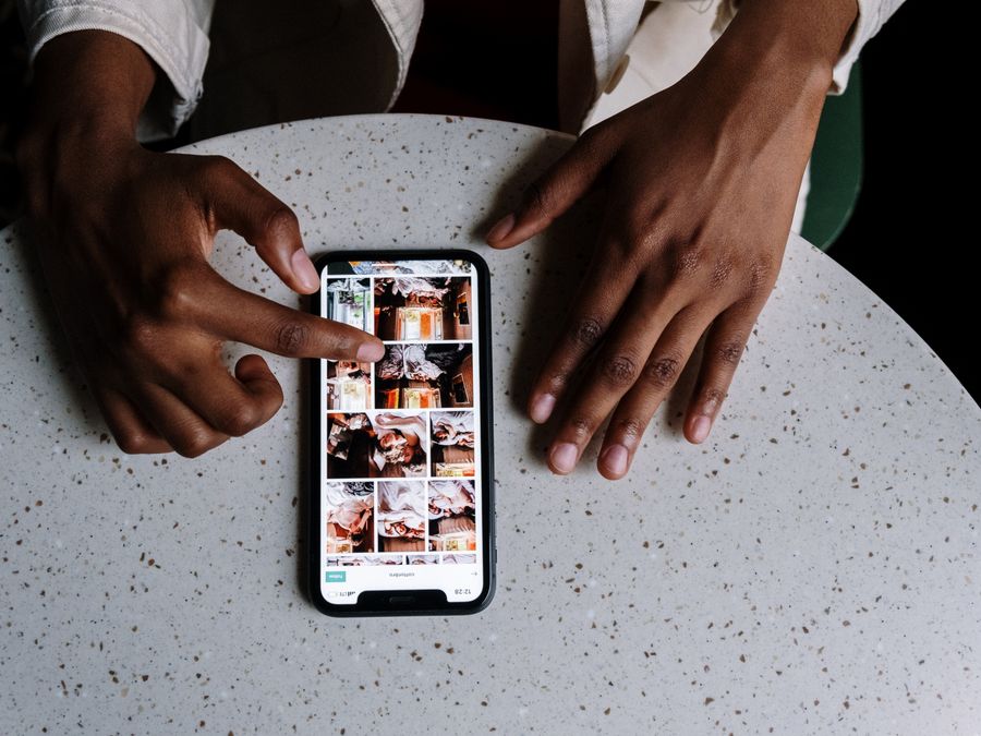 Hands interacting with smartphone displaying social media content on table in cafe setting.