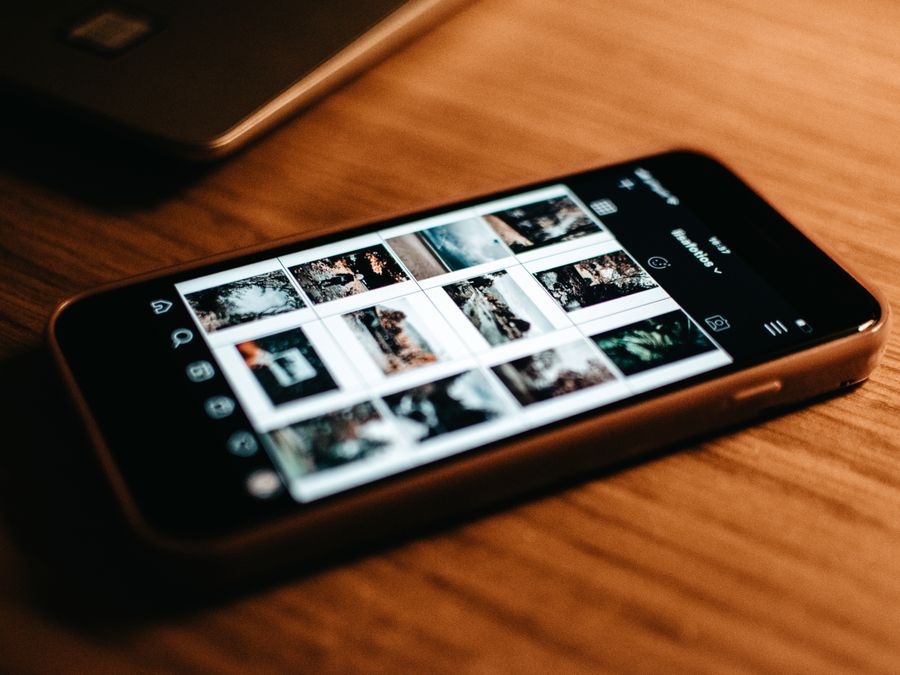 Close-up of smartphone showing photo gallery on wooden desk.