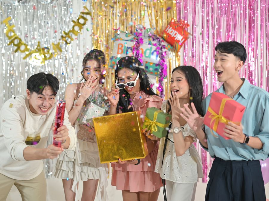 Group of friends celebrating a birthday indoors with gifts and decorations.