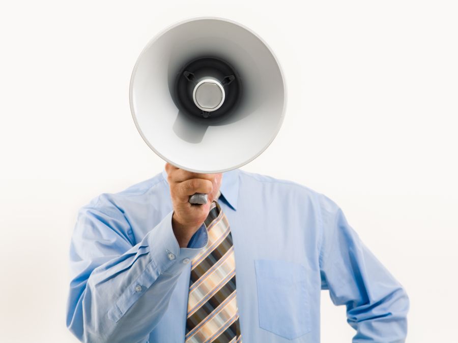 Businessman in blue shirt holding megaphone, symbolizing leadership and communication.