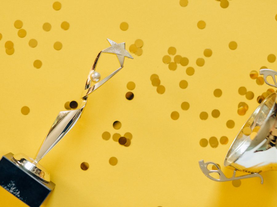 Golden trophy with celebratory confetti on a vibrant yellow background.