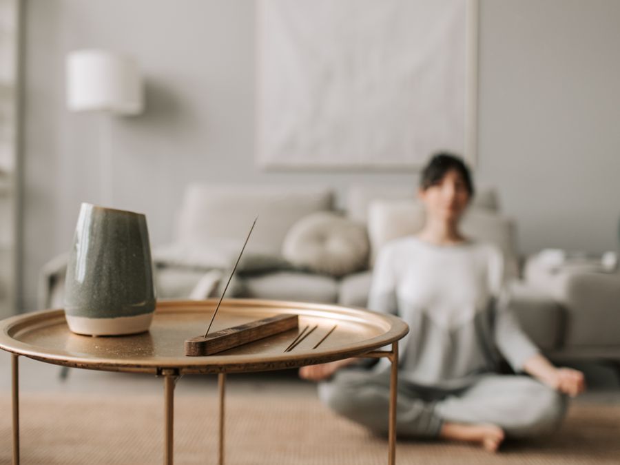 Calm living room scene with incense and a woman meditating, perfect for relaxation concepts.