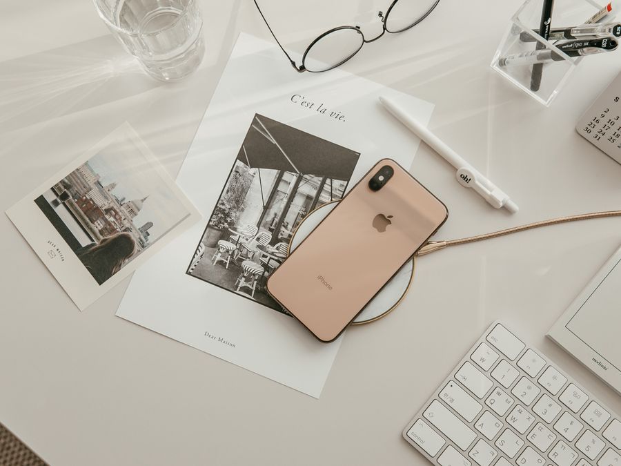 Aesthetic workspace featuring a smartphone, keyboard, and stationery in a warm, minimalist setup.